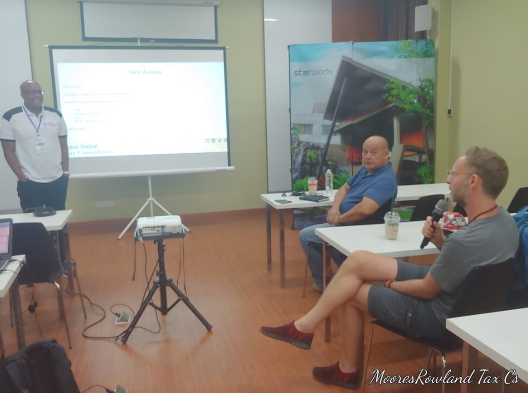Men in a presentation room with a projector screen and a large banner.