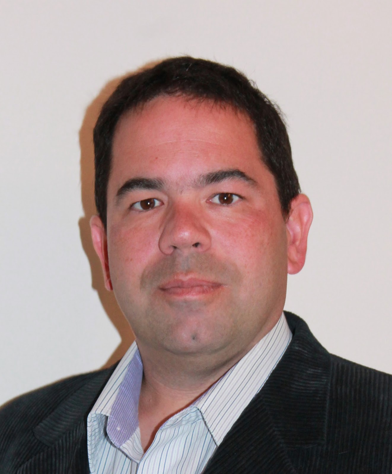 Patrick Poulin, a man with dark hair, wearing a striped shirt and dark jacket.