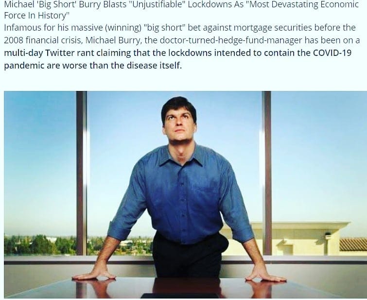 Man in blue shirt leaning on a table looking up, with a window behind him.