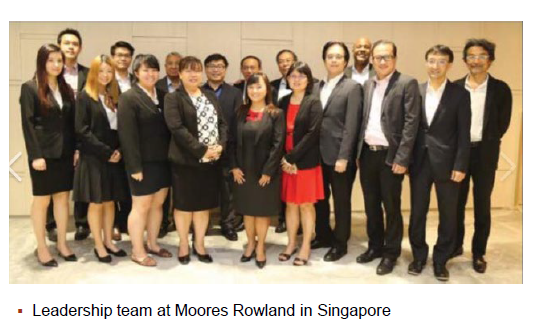 A group of men and women in business attire pose for a photo.