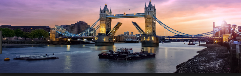 Tower Bridge in London at sunset with boats on the Thames River.