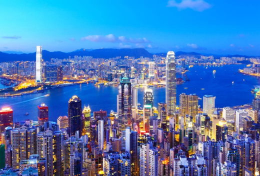 Hong Kong skyline at dusk with illuminated skyscrapers and harbor.