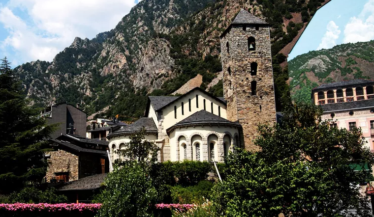 Stone church tower and buildings nestled in a mountain valley.