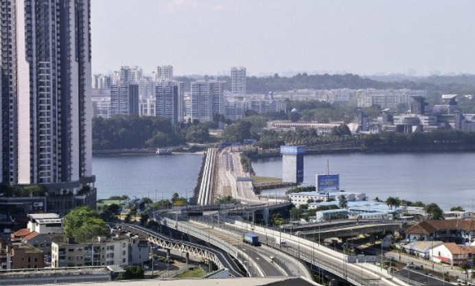 Elevated highway overpass with traffic and buildings in the background.