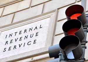 Traffic light with red lights facing a building labeled Internal Revenue Service.