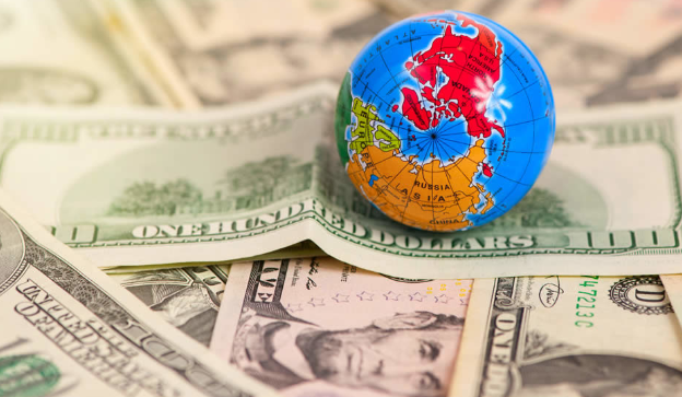 Small globe resting on U.S. dollar bills.