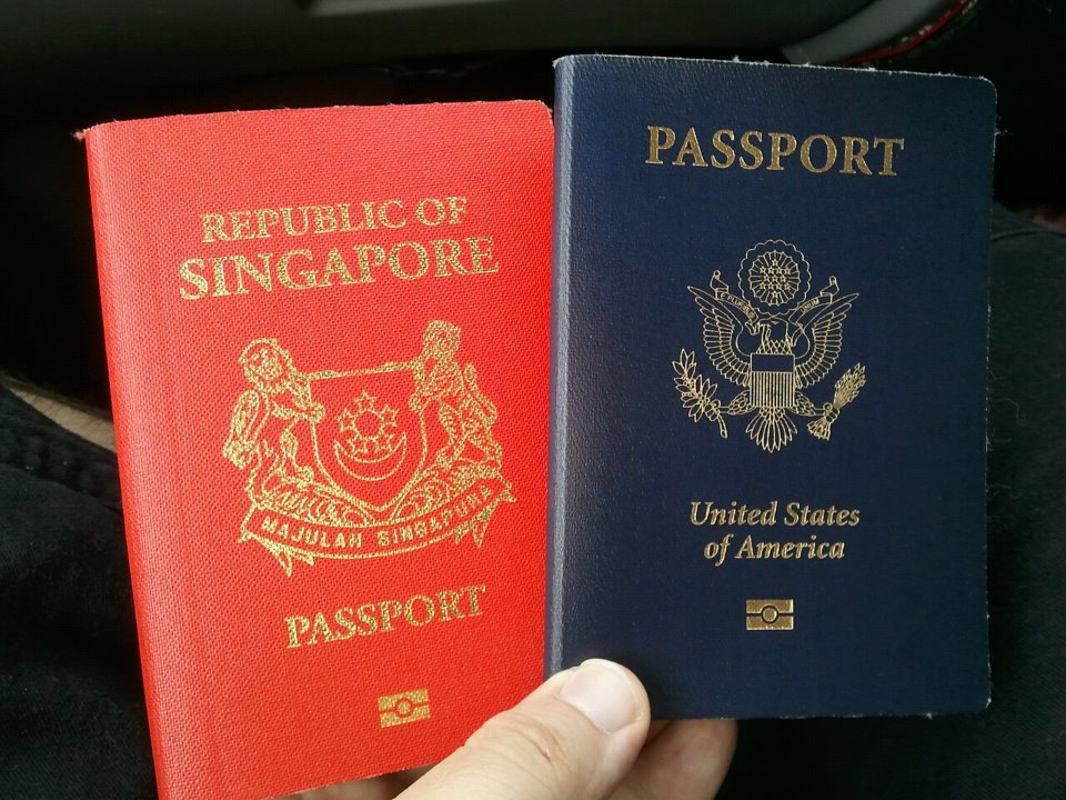 Singapore and United States passports held by a hand.