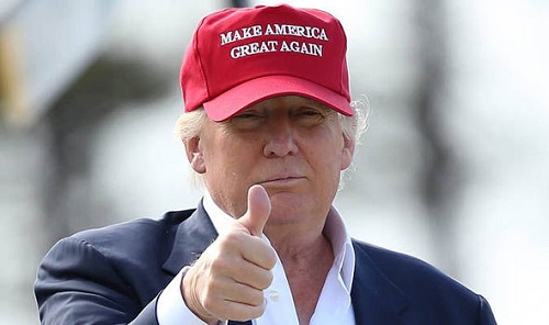 Donald Trump wearing a red Make America Great Again hat and giving a thumbs up.