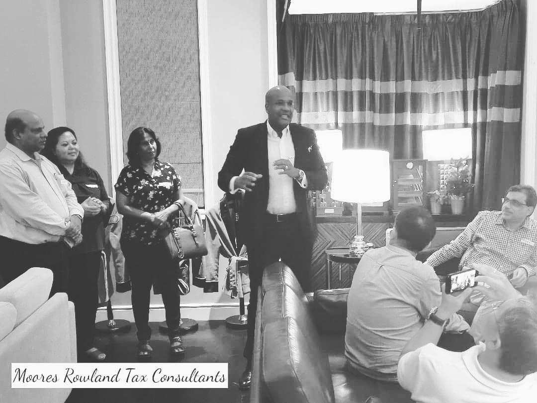 Moores Rowland Tax Consultants logo on black and white photo of people in a room.