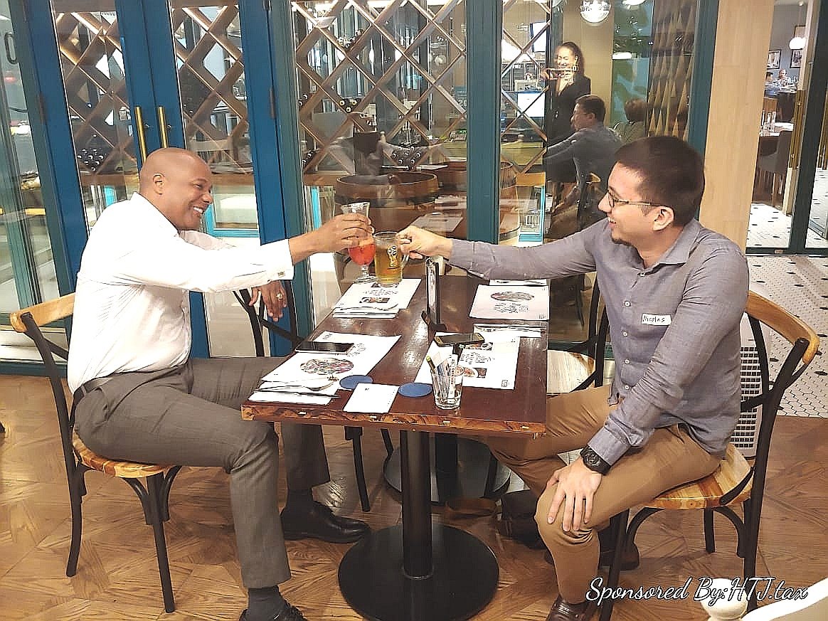 Two men toasting drinks at a table in a restaurant.